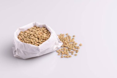 Beyaz bir kağıt torba içinde kuru pişmemiş mercimek açı görünümü, beyaz arka plan üzerinde izole
