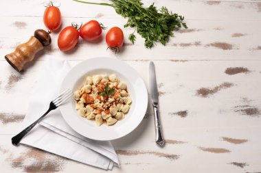 İtalyan tortellini (capeletti, agnolini) rustik beyaz ahşap masa arka plan üzerinde beyaz bir tabak domates sosu ile