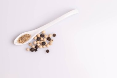 Beyaz arka plan üzerinde izole beyaz bir kaşık siyah beyaz biber