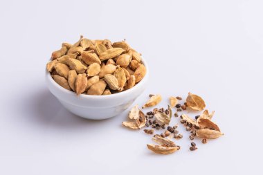 Beyaz bir kase kuru Kakule pod Açı görünümü, beyaz arka plan üzerinde izole, latince terim Elettaria kakule