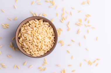 Siyah seramik bolw Orzo makarna, beyaz arka plan üzerinde izole. Pirinç taneleri şeklinde İtalyan orzo makarna