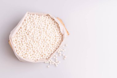 Beyaz arka plan üzerinde izole bir kağıt torba içinde tapyoka inci veya sagu tohumu üst görünümü