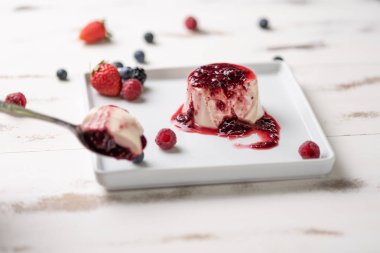 Berry soslu lezzetli İtalyan tatlı panna cotta, beyaz ahşap arka plan taze çilek