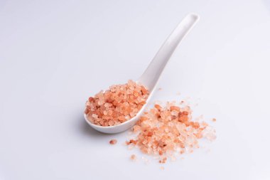 Beyaz arka plan üzerinde beyaz bir kaşık pembe himalaya tuzu