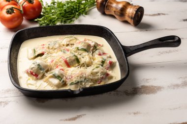 siyah demir tavada çok renkli ravioli makarna, ahşap beyaz masa arka plan üzerinde. 