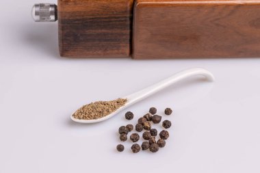 Beyaz arka plan üzerinde izole beyaz bir kaşık siyah beyaz biber. 