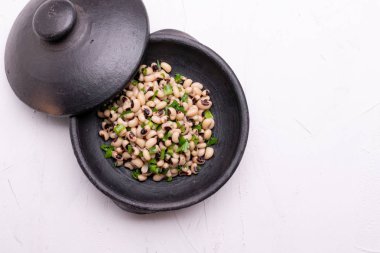 Beyaz arka plan üzerinde izole siyah kil tencerede pişmiş fradinho fasulye salatası,.