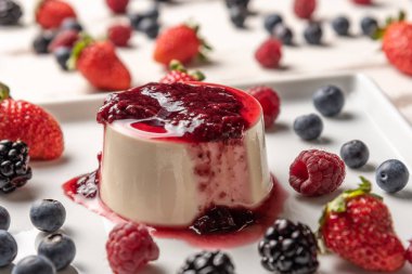 Berry soslu lezzetli İtalyan tatlı panna cotta, beyaz ahşap arka plan taze çilek