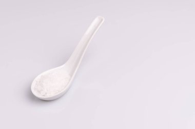 Beyaz arka plan üzerinde izole beyaz bir kaşık kaba deniz tuzu açı görünümü