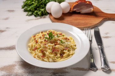 Pancetta, yumurta, sert parmesan peyniri ve krema soslu carbonara makarna. Beyaz ahşap arka plan üzerinde beyaz plaka. 