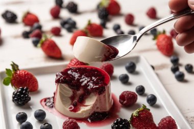 Berry soslu lezzetli İtalyan tatlı panna cotta, beyaz ahşap arka plan taze çilek