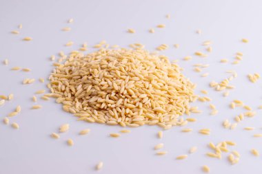 Beyaz arka planda izole edilmiş beyaz seramik bir makarna yığını. Pirinç tanesine benzeyen İtalyan orzo makarnası.