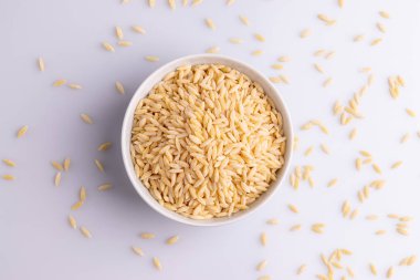 Beyaz seramik bolw Orzo makarna, beyaz arka plan üzerinde izole. Pirinç taneleri şeklinde İtalyan orzo makarna