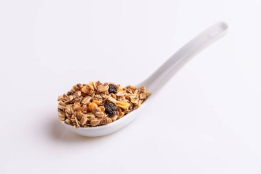 Granola veya müsli fındık ve rasins beyaz bir arka plan üzerinde beyaz bir kaşık