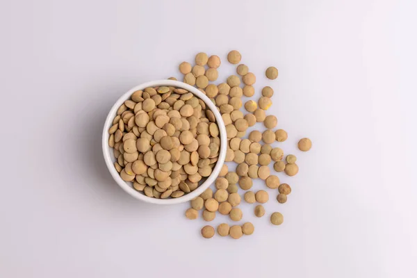 白いセラミックボウルに入った乾燥した未調理のレンズ豆のトップビュー 白い背景に隔離 — ストック写真