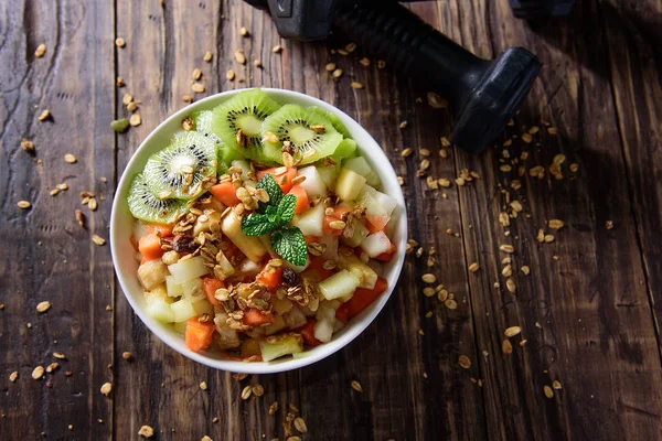 Breakfast with muesli, kiwi salad, fresh fruit, on dark background. Healthy food concept.