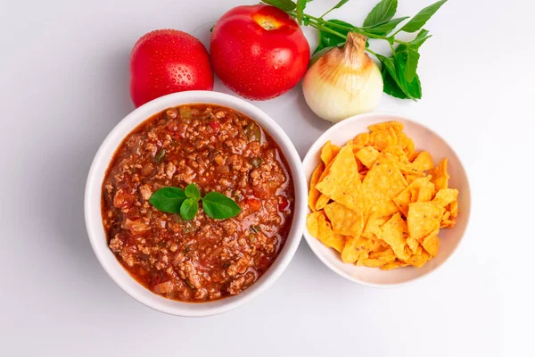 Bolognese (ayrıca Bolognesa veya Bolonhesa olarak da bilin) beyaz arka planda izole beyaz bir kapta sos ve mısır cipsi nachos