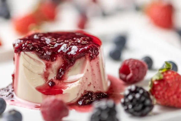 Berry soslu lezzetli İtalyan tatlı panna cotta, beyaz ahşap arka plan taze çilek
