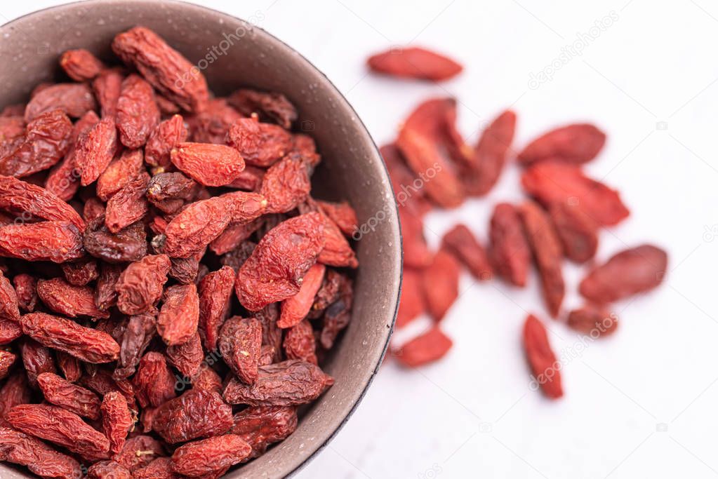 Top view of Goji berries in a brown bolw, isolated on white background.