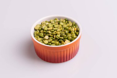 Bölünmüş bir portakal ramekin içinde pişmiş pişmemiş bezelye, beyaz arka plan üzerinde izole