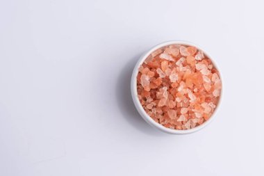 Beyaz arka plan üzerinde beyaz bir kapta pembe himalaya tuzu