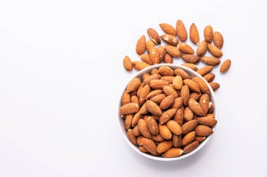Beyaz bir kapta badem fındık yığını üst görünümü, beyaz arka plan üzerinde izole