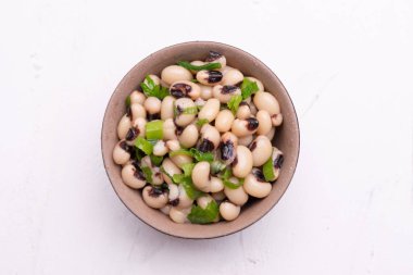 Beyaz bir arka plan üzerinde izole siyah kil tencerede Pişmiş Fradinho fasulye salatası