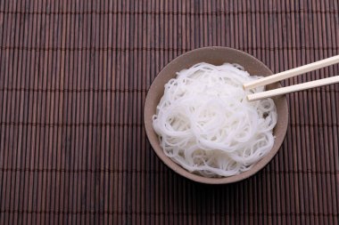 Pişmiş pirinç erişte ahşap arka plan üzerinde izole çubukları ile kase Tay tarzı.