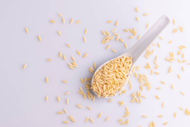 Beyaz seramik kaşıkta Orzo makarna, beyaz arka plan üzerinde izole. 