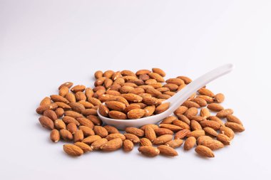 Beyaz bir kaşık badem fındık yığını açı görünümü, beyaz arka plan üzerinde izole