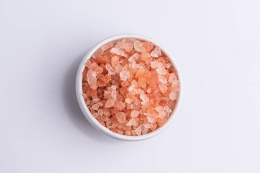 Beyaz arka plan üzerinde beyaz bir kapta pembe himalaya tuzu