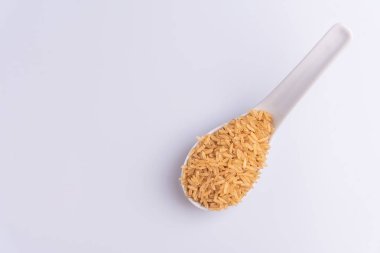 Beyaz arka plan üzerinde beyaz bir kaşık Ham Kahverengi Pirinç Üst görünümü