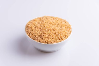 Beyaz arka plan, açı görünümü üzerinde beyaz bir kapta Ham Kahverengi Pirinç Açı görünümü. İntegral Kepekli Tahıl. Latince terim Oryza sativa da Tüm Çin Pirinç tohumu olarak bilinen