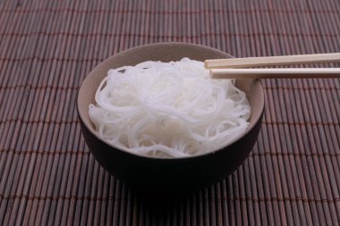 Pişmiş pirinç erişte ahşap arka plan üzerinde izole çubukları ile kase Tay tarzı.