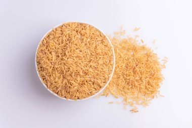 Beyaz arka plan, açı görünümü üzerinde beyaz bir kapta Raw Brown Rice üst görünümü. İntegral Kepekli Tahıl. Latince terim Oryza sativa da Tüm Çin Pirinç tohumu olarak bilinen