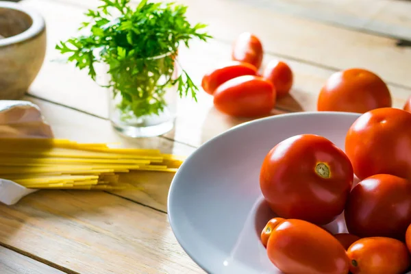Tahta masada taze domates ve çiğ spagetti. 