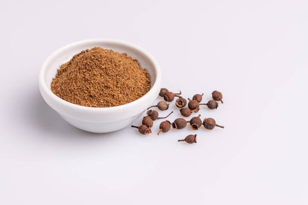 Ground allspice в белой керамической миске, изолированной на белом фоне
