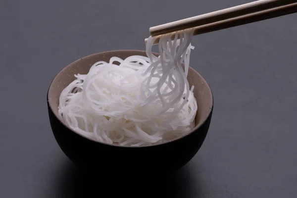 Cooked rice noodle Thai style in bowl with chopsticks isolated on black background