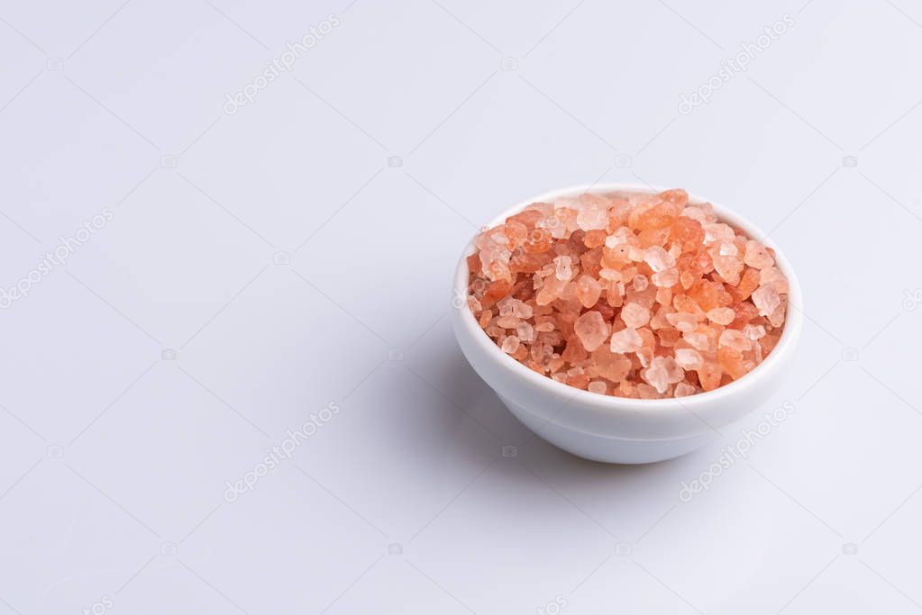 Pink himalayan salt in a white bowl on white background