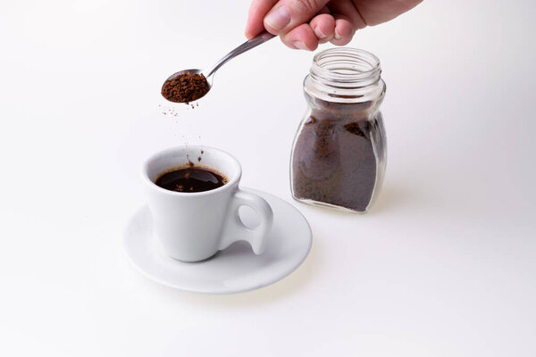 Мгновенный гранулированный кофе из чашки кофе на белом фоне
