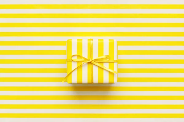 Yellow gift box on white & yellow striped wrapping paper. Minimal geometric background for card, flyer, invitation, placard or voucher.