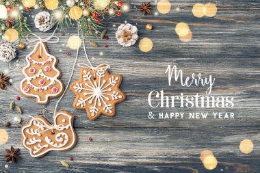 Metin neşeli Noel ve mutlu yeni yıl, Gingerbread çerezleri ve Noel süslemeleri tatil tebrik kartı üzerinde. Garland ışıkları parlayan.