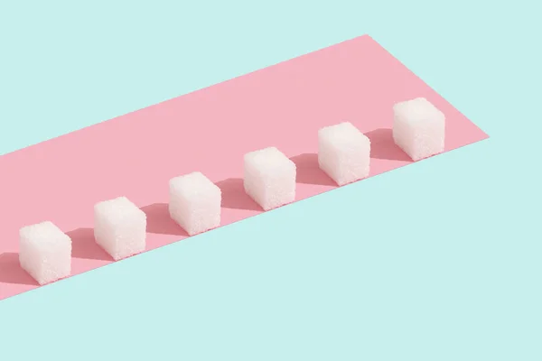 Kostky cukru v řadě na růžovém a modrém pozadí v minimálním stylu — Stock fotografie
