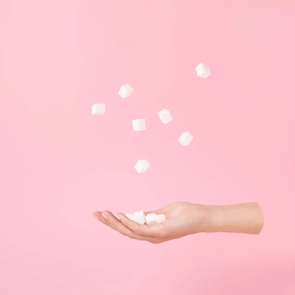 Mano voladora y cubos de azúcar levitación sobre rosa Estilo minimalista o surrealista . — Foto de Stock