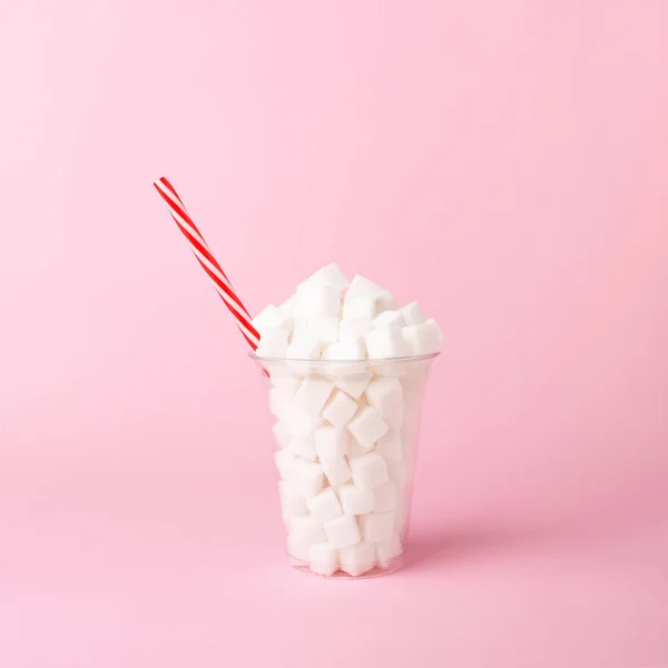 Plastový šálek se slámou plnou kostek cukru na růžovém pozadí koncepce nezdravých nápojů — Stock fotografie