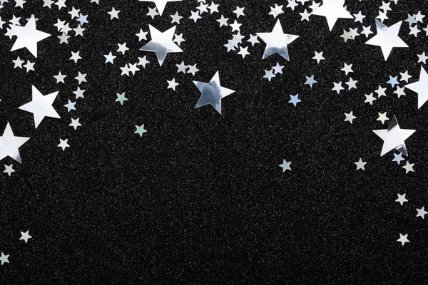 Padající stříbrné hvězdy konfety na černém slavnostním pozadí zářící jiskřicí rám. — Stock fotografie