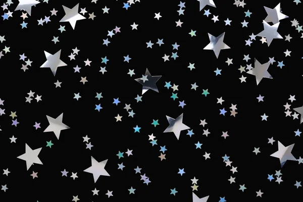 Silver stars confetti isolated on black Festive holiday background Sparkles overlay.