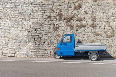Mavi, küçük taşıma aracı önünde parlak bir taş duvar