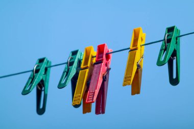 Çamaşır ipinde asılı renkli mandallar.