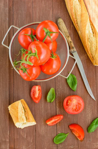 Bir ahşap tepsi bir kapta taze domates ve bir baget yalan